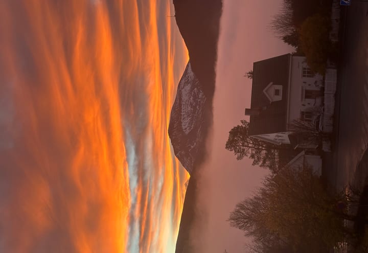 Orange sunset over a misty Nordic mountain and village street