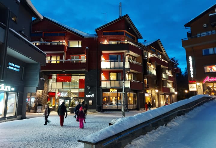 Levi centre with hotels, shops and skiers on a snowy evening