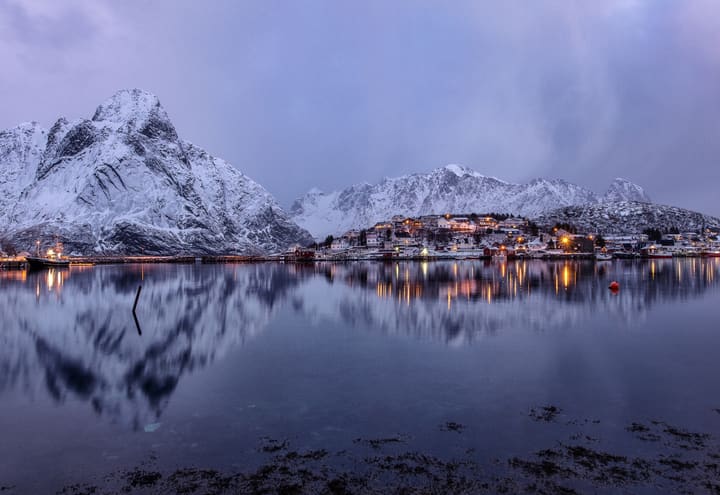 Reine in Lofoten in winter with snow-covered peaks reflected in the still fjord